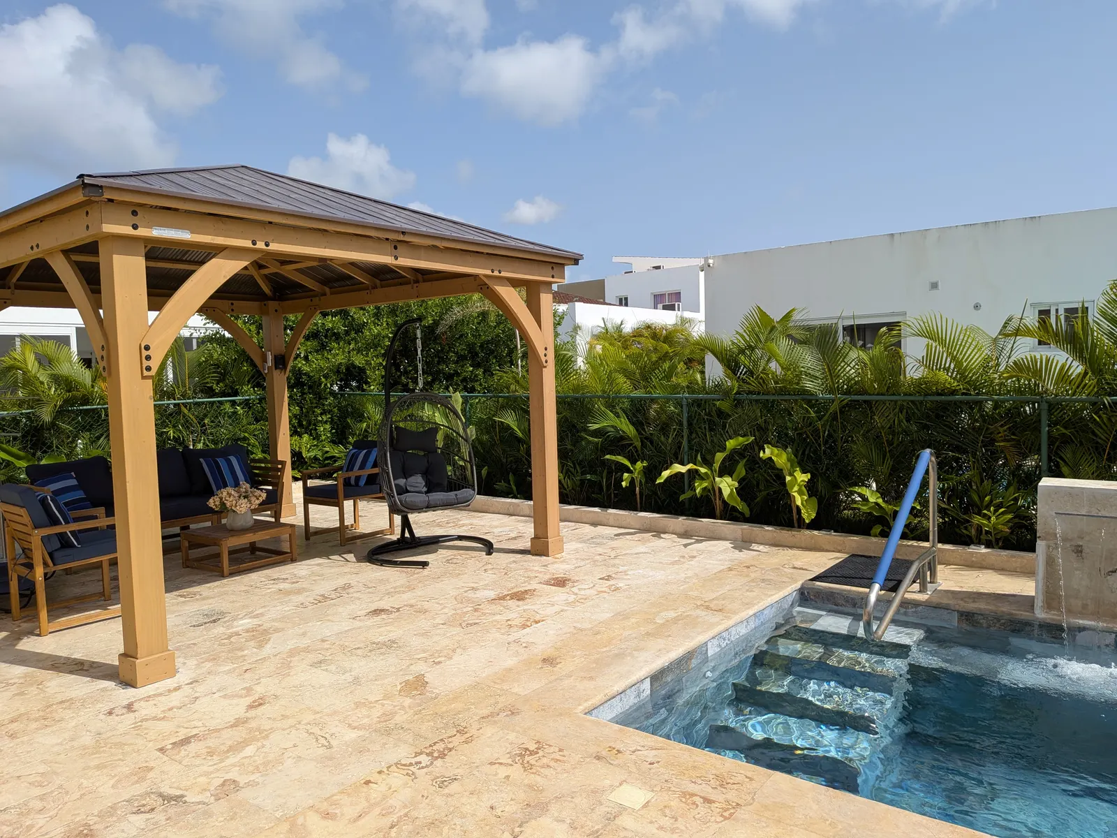 The wood gazebo lounge with its hanging egg chair beside the pool