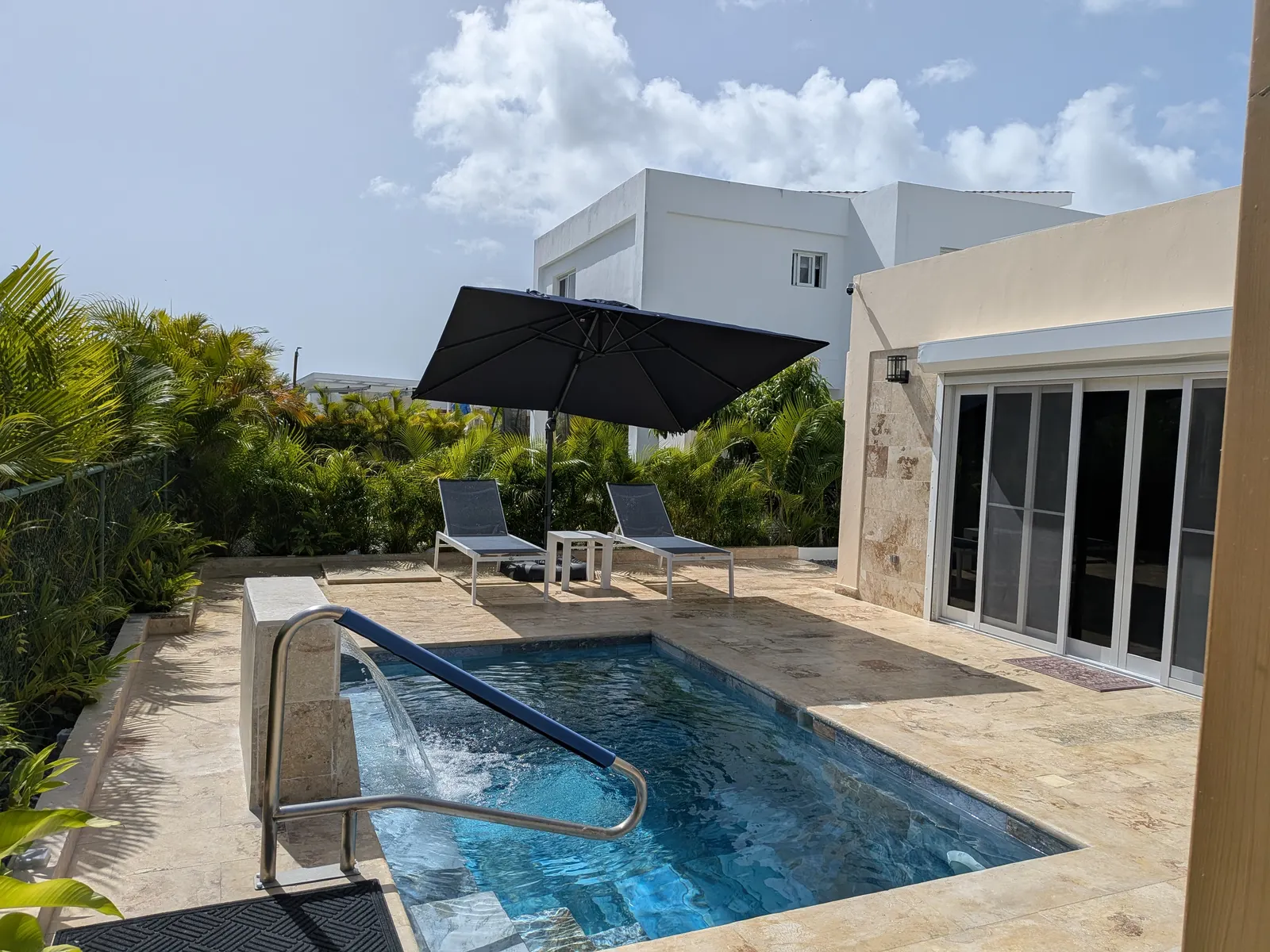 The waterfall pouring into the private pool beside the umbrella and loungers
